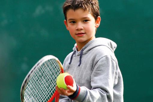 Boy serving mini tennis ball